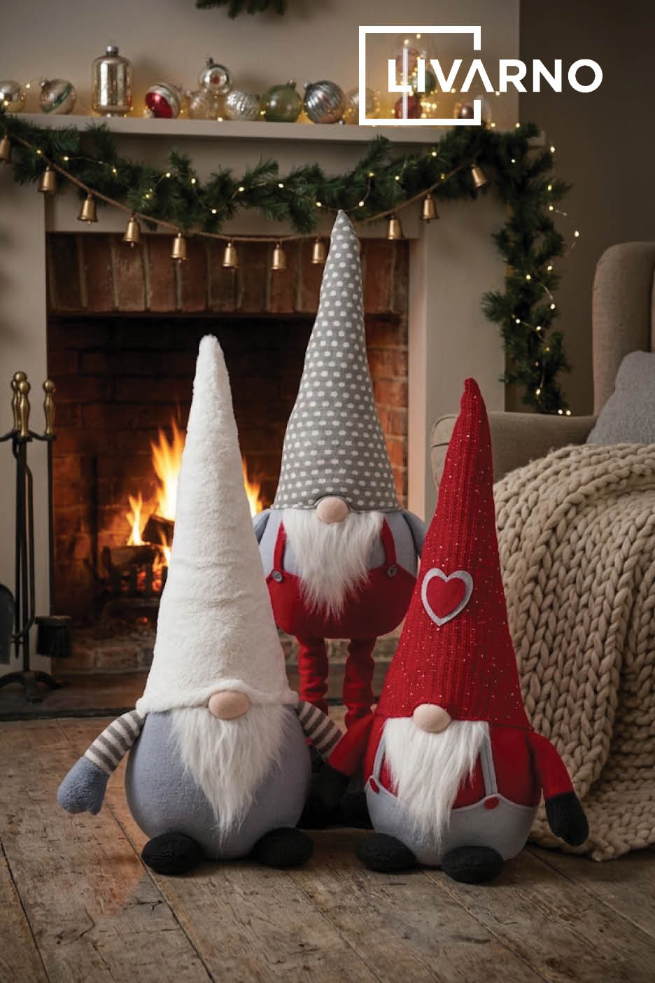 Trois gnomes de Noël décoratifs posés devant une cheminée chaleureuse.