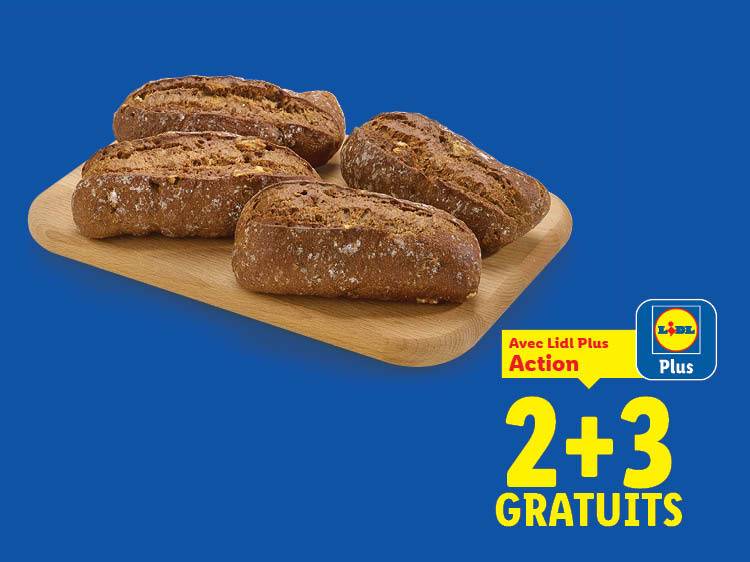 Quatre petits pains bruns sur une planche en bois, avec une offre 2+3 gratuits.