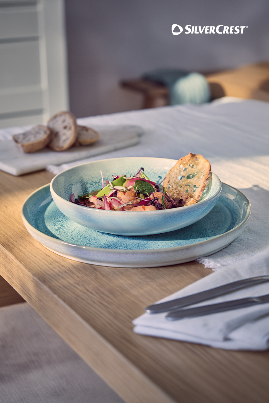 Un bol de salade de saumon et un plat en céramique sur une table en bois.
