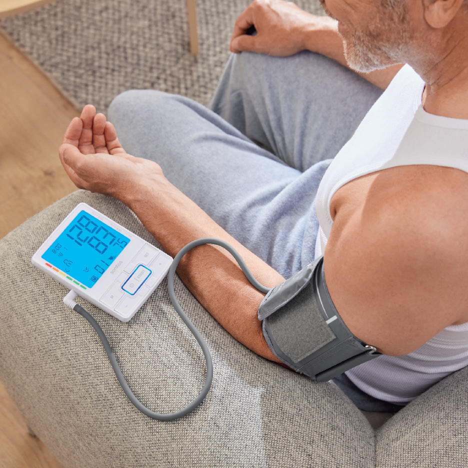 Un homme mesure sa tension artérielle avec un tensiomètre numérique à domicile.